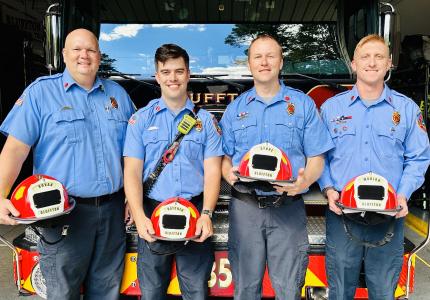 Lieutenants standing in front of fire engine holding new helmets