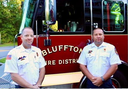 Battalion Chiefs Derek Franks and Jayme Beach standing in front of fire engine